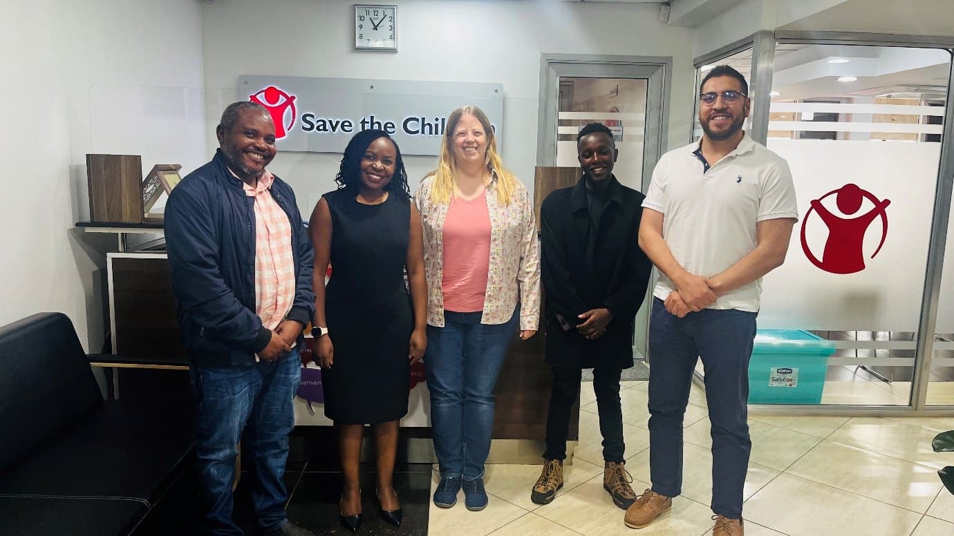 Five colleagues standing together in a Save the Children office reception.