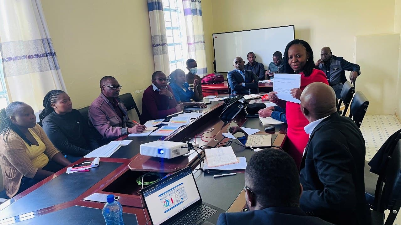 Health care workers seated around a conference table during a WASH FIT training session.